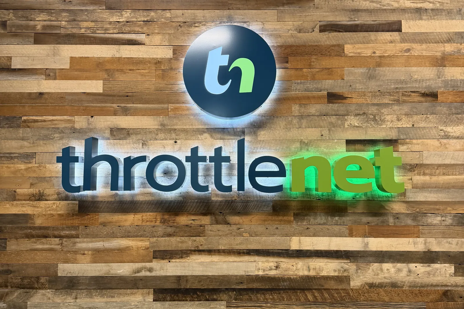 The ThrottleNet logo on a reclaimed-wood wall at the company headquarters