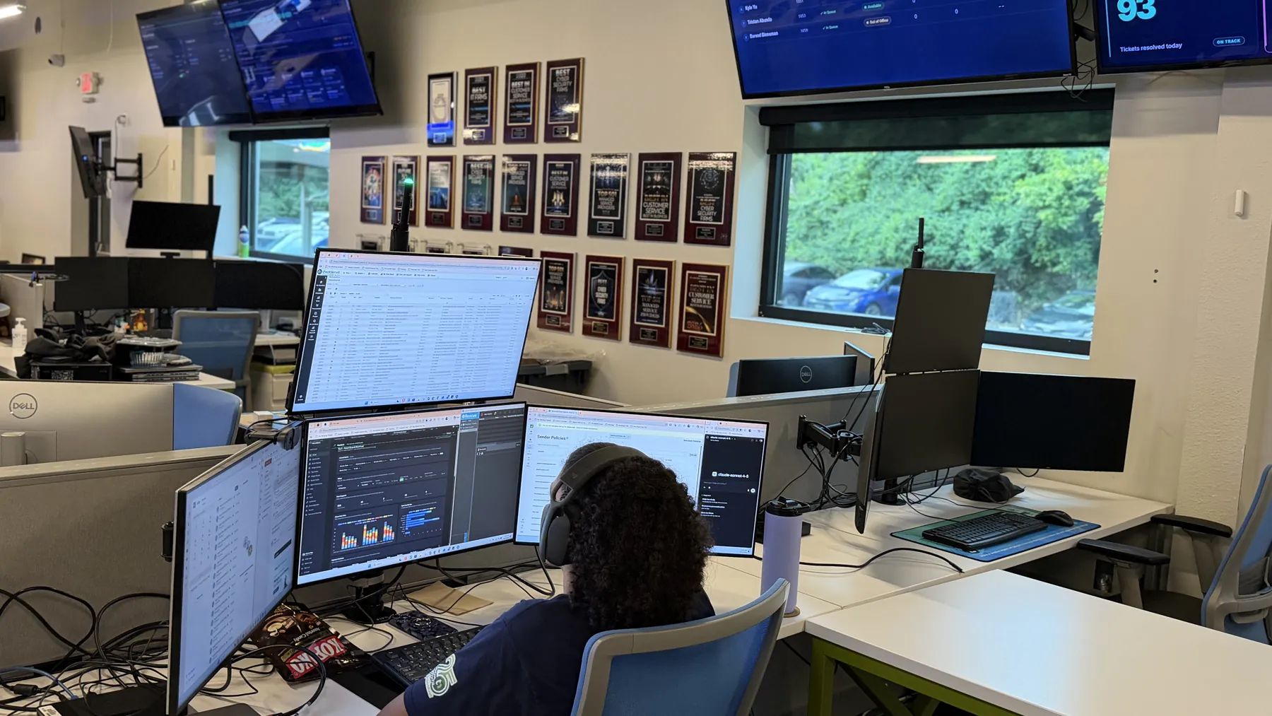 A ThrottleNet help desk technician working an incident across several monitors under live queue dashboards