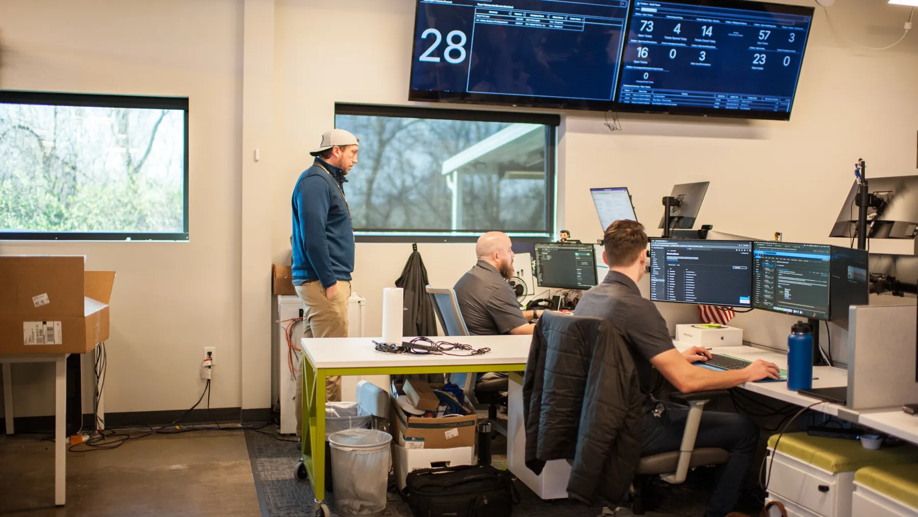 ThrottleNet operations room with technicians at desks below wall-mounted queue dashboards