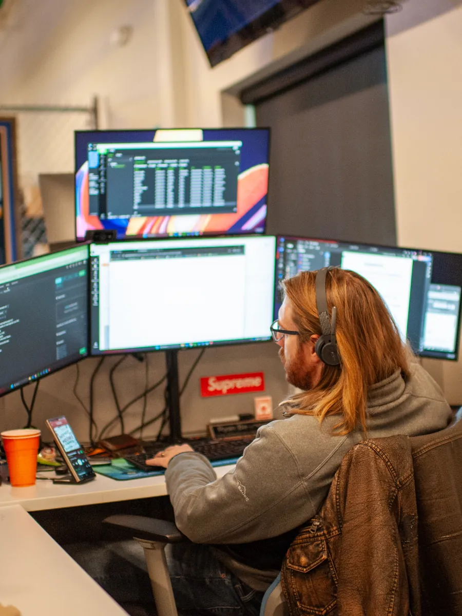 A ThrottleNet help desk technician on a headset at a three-monitor workstation